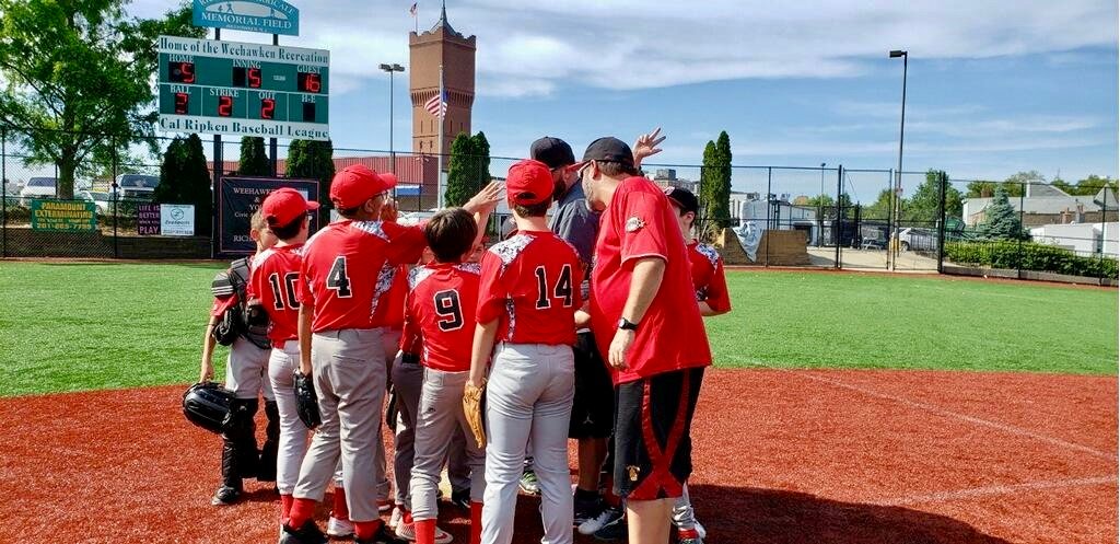 Boys baseball team huddle water tower and scoreboard in background